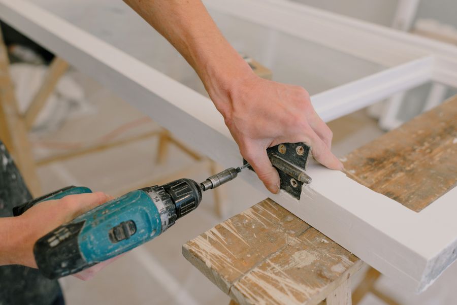 Handyman installing a hinge with a drill