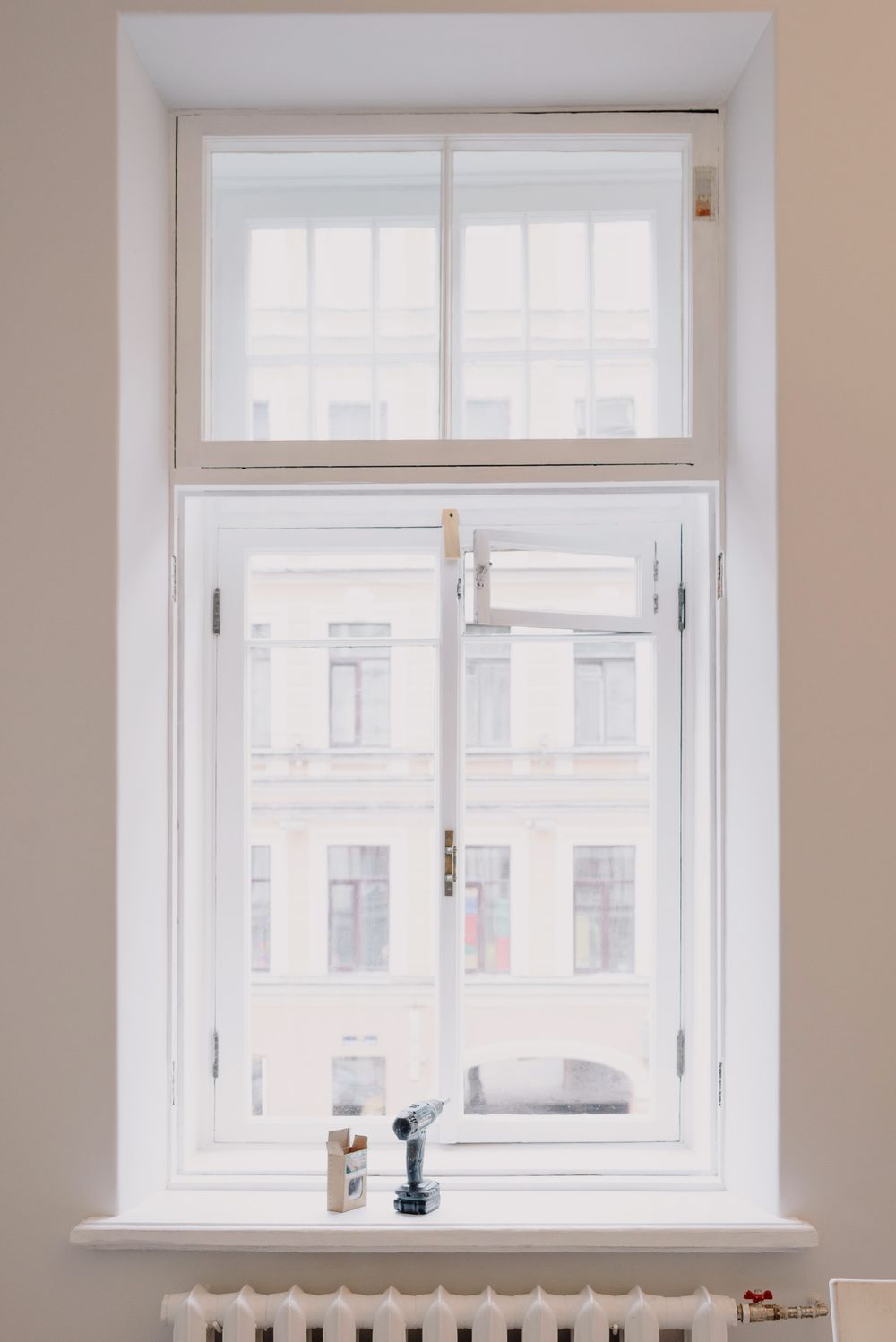 A newly installed wooden window with a white frame, tools resting on the sill