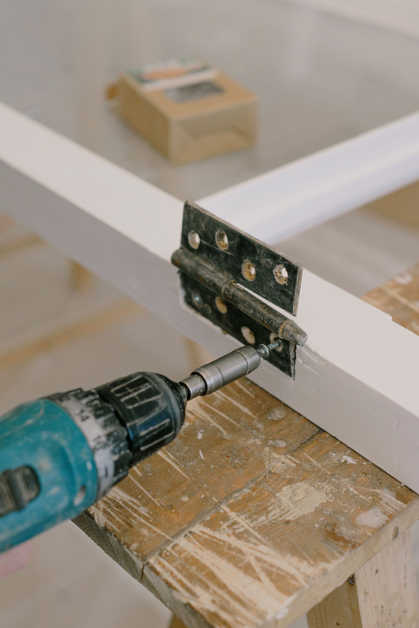 Power screwdriver fastening metal hardware to a wooden frame