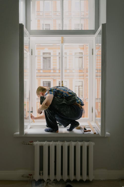 Free Anonymous man on windowsill during repair work Stock Photo