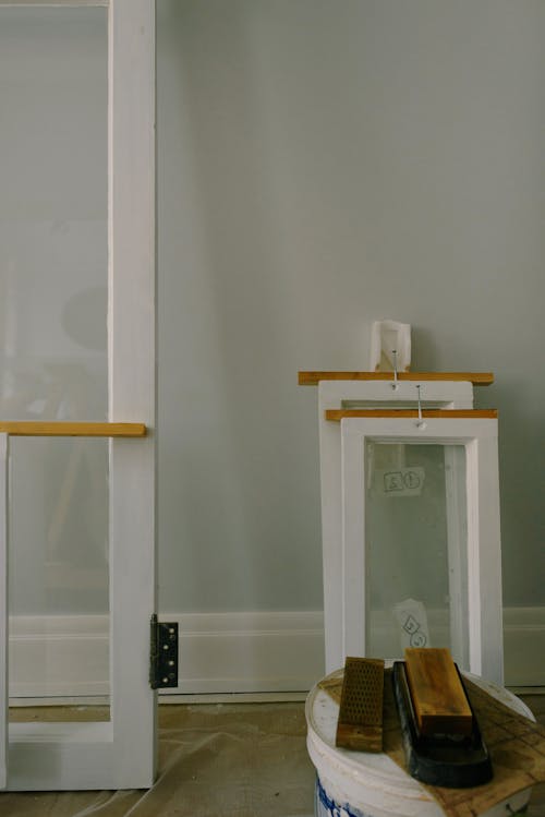 White window frames with hinge on floor with paint container in flat during renovation