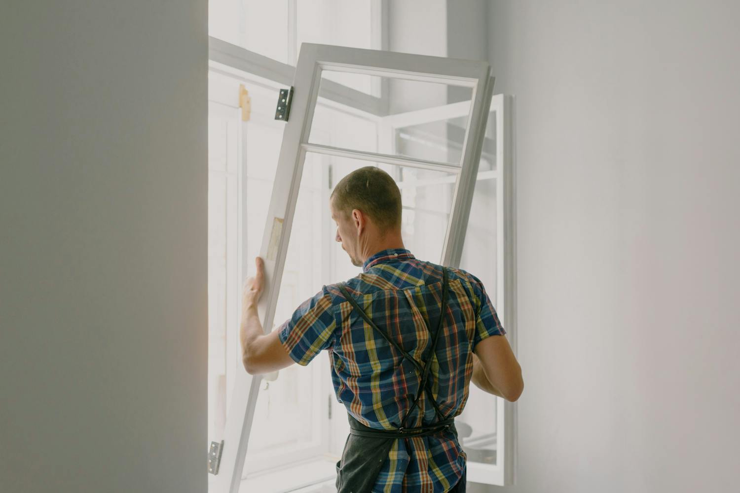 A professional installer fitting a modern window in a well-lit home interior.