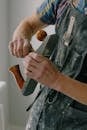 Crop unrecognizable workman in dirty apron with manual jointer near wall in apartment during renovation process