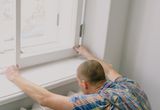 Fitter installing a new window indoors