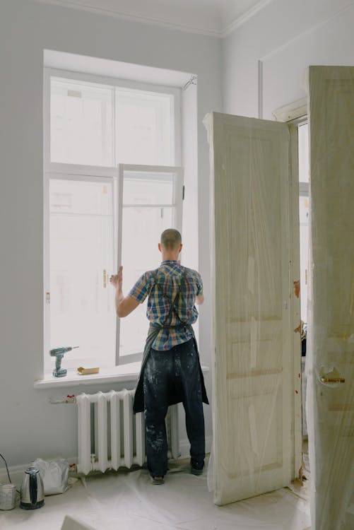 Free Faceless handyman mounting window in new house Stock Photo