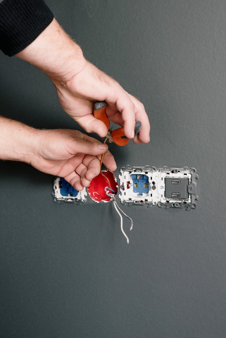 An Electrician Using Pliers To Repair The AC Power Plugs And Sockets