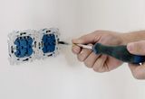 Hands using a screwdriver to install an electrical socket on a white wall