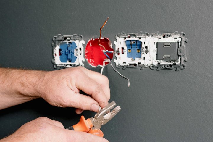Aluminum wiring pigtail repair in Orem Electrician using pliers to repair the wiring behind an outlet