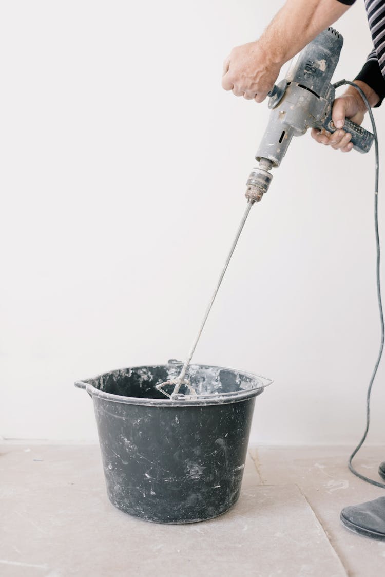 Crop Man Mixing Cement In Room