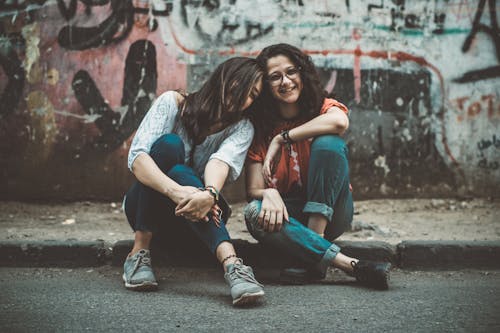 gratis Twee Vrouwen Zittend Op De Stoep In De Buurt Van Geschilderde Muur Stockfoto