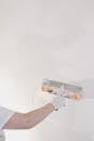 Crop man plastering wall at home