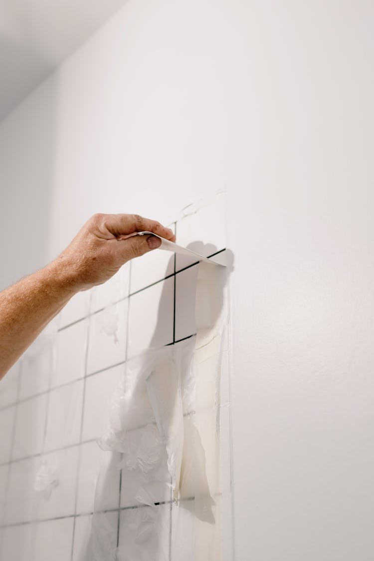 Crop Man Repairing Tiled Wall In Room