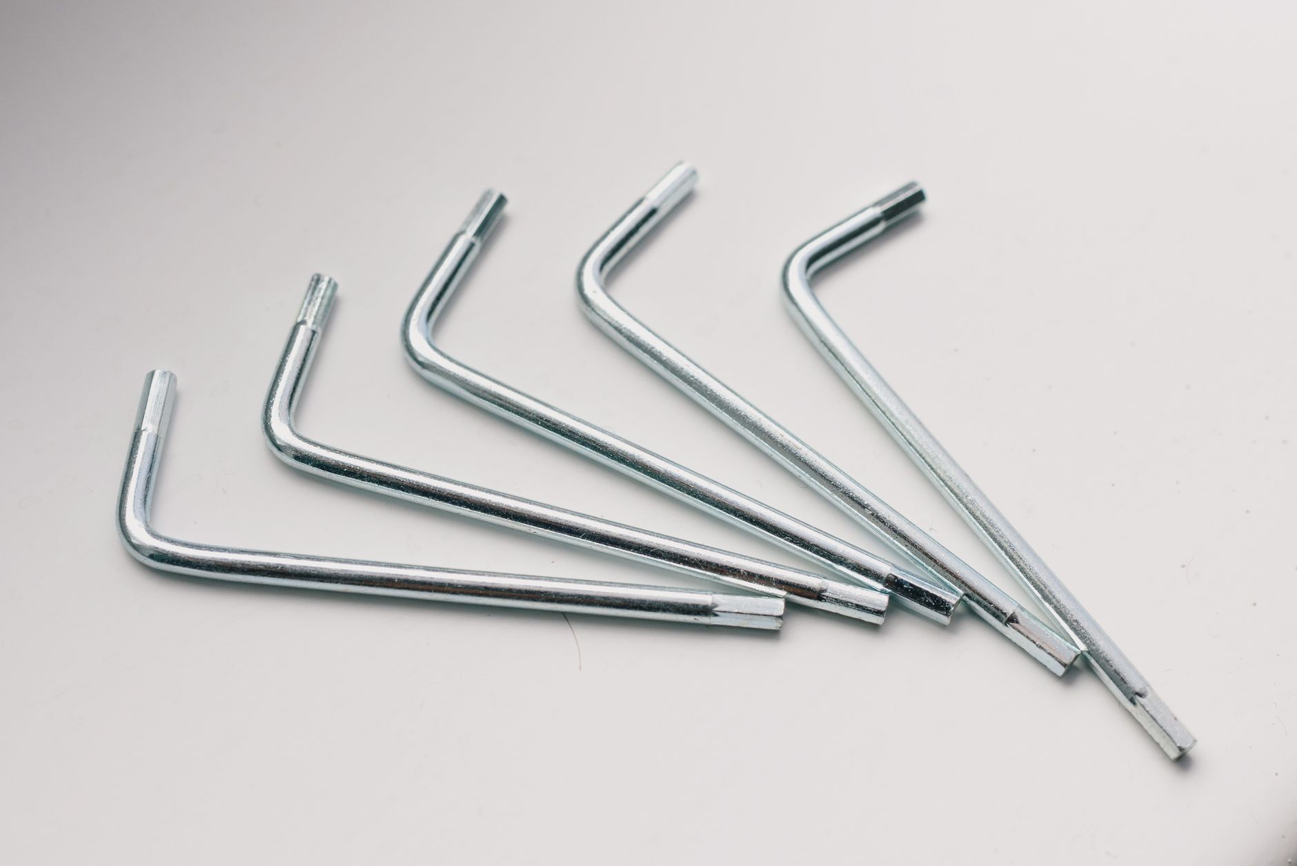 From above of collection of different metallic hex keys on white table in workshop