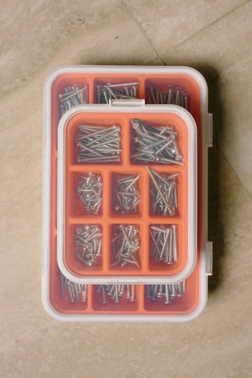 From above of different metal nails and bolts in plastic boxes on marble table