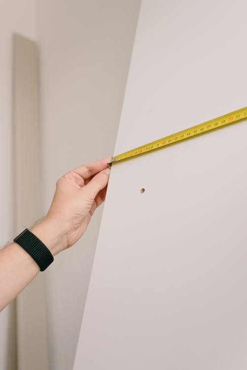 person measuring a wall with a tape