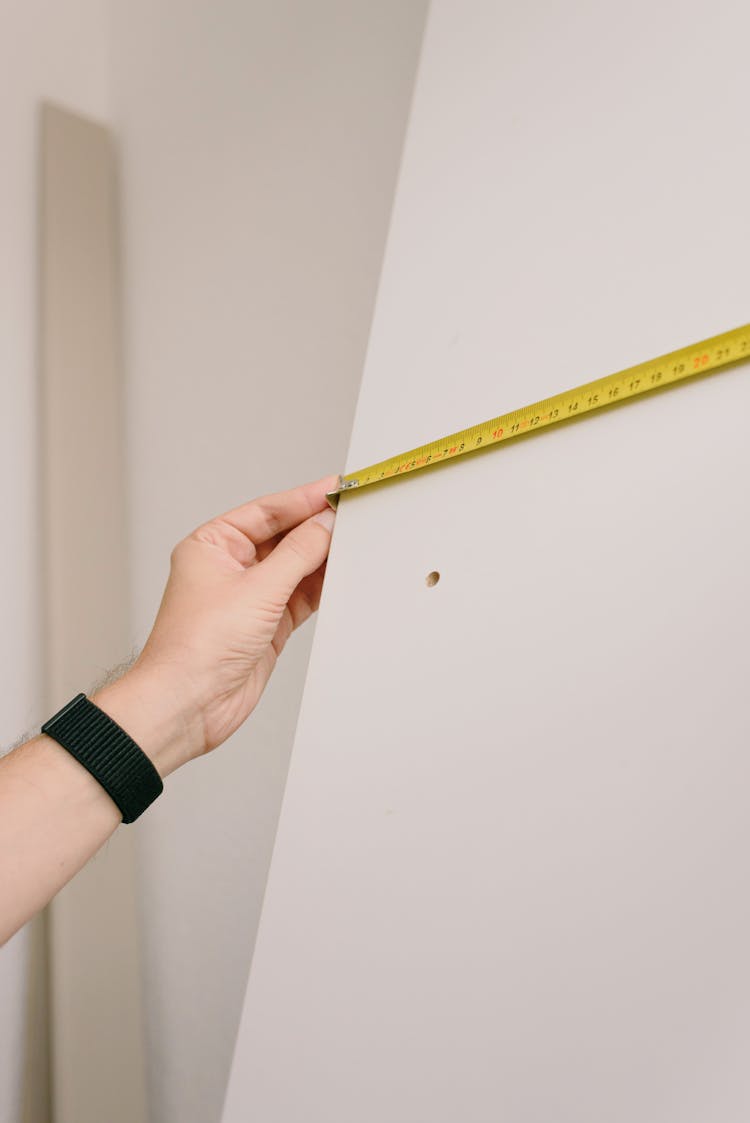 Crop Man Measuring Wall In Room