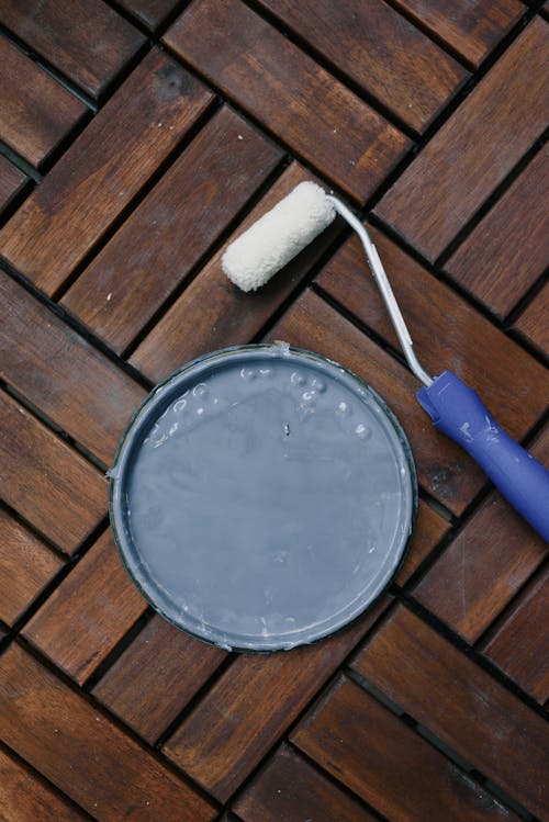 From above of clean paintbrush and plastic cap on wooden floor at home