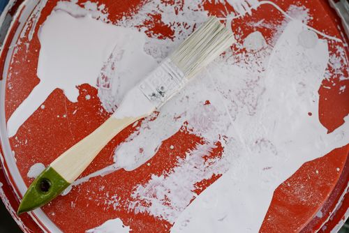 Free From above of brush with white paint on dirty plastic surface during repair Stock Photo