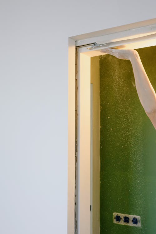 Crop woman peeling doorway at home