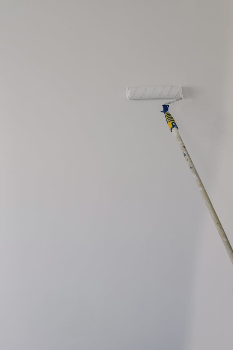 Paint Roller On White Wall At Home