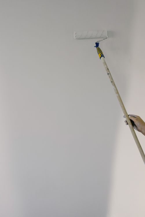 Aplicação de tinta com rolo em parede clara de imóvel residencial