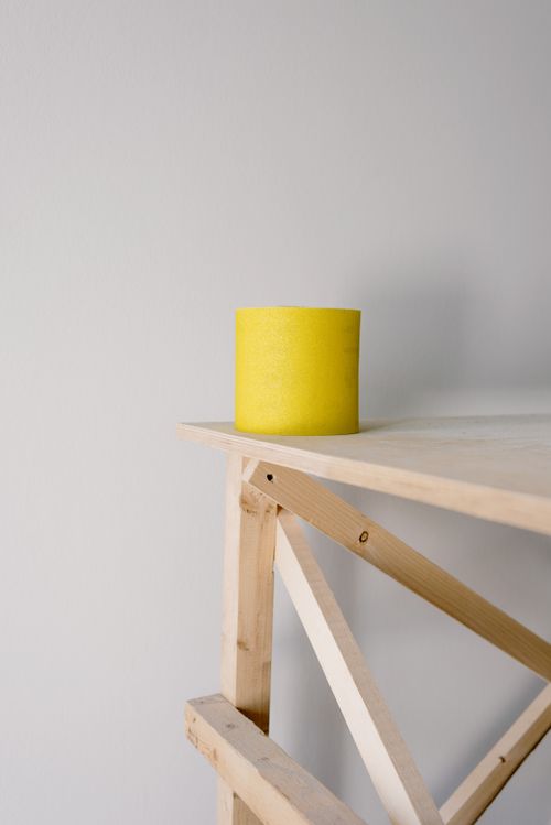 Free Yellow sandpaper roll placed on wooden scaffold placed in light flat against white wall during renovation Stock Photo