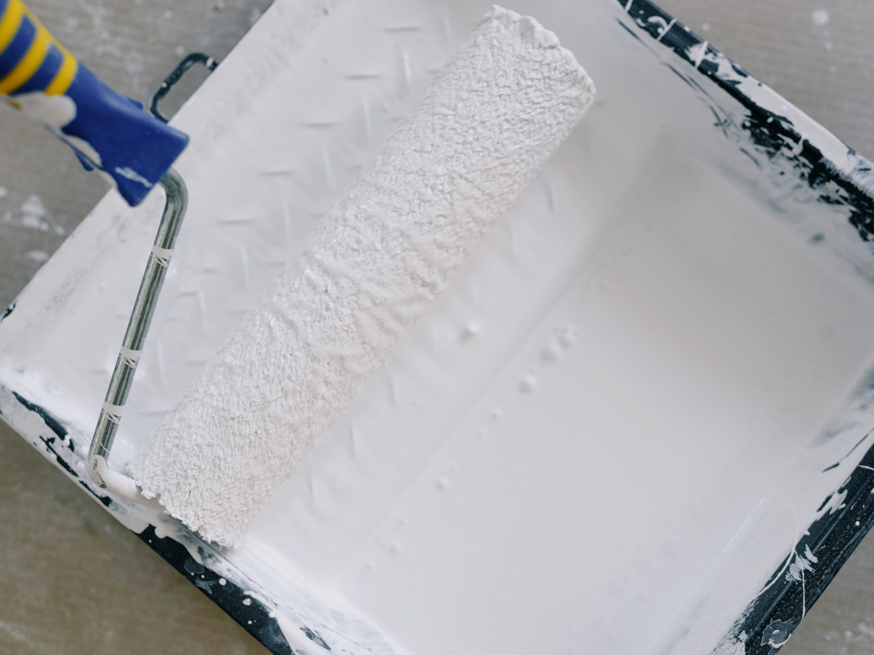 Paint roller and tray on a dust-sheeted floor mid-renovation