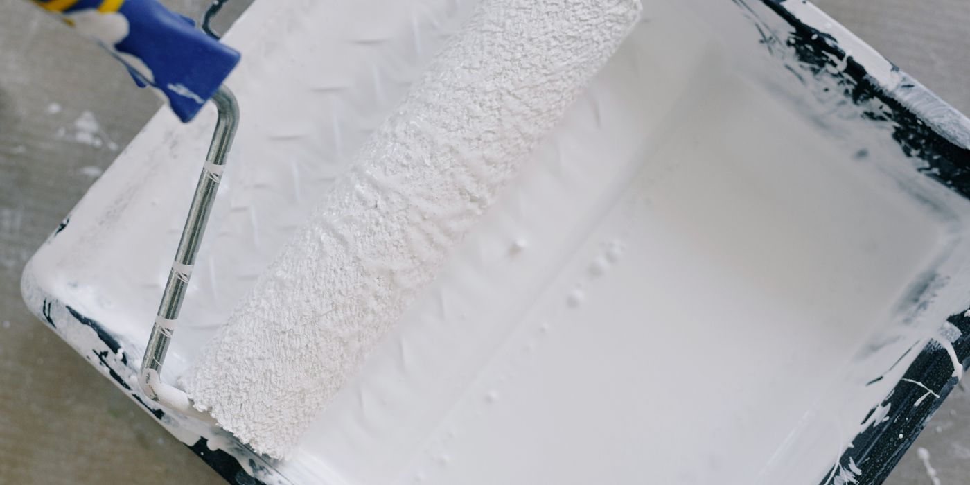 A roller loaded with white coating resting in a tray