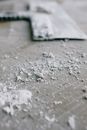 Dirty paint scraper placed on parquet covered with old white paint in light apartment during renovation