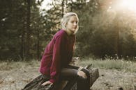 一名年轻女子穿着休闲装，坐在宁静森林里的浮木上