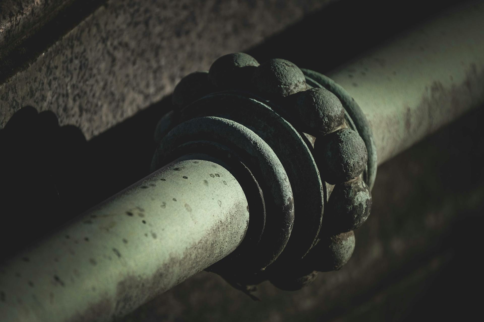 Close-up of a weathered and rusty industrial pipe with detailed grunge texture in low light.