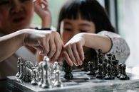 一名年轻女孩在安静的室内与家人一起学习国际象棋