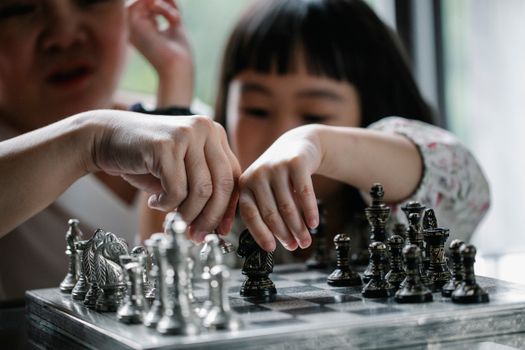 一名年轻女孩在安静的室内与家人一起学习国际象棋
