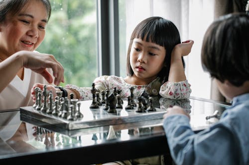 Mother and children playing chess at home