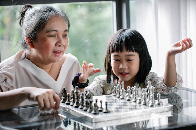 Asian Grandmother Teaching Cute Granddaughter To Play Chess