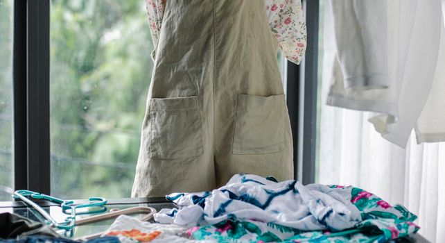 Crop faceless woman choosing outfit from clothes heap on table