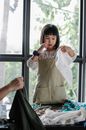 Positive Asian girl choosing clothes heaped on table