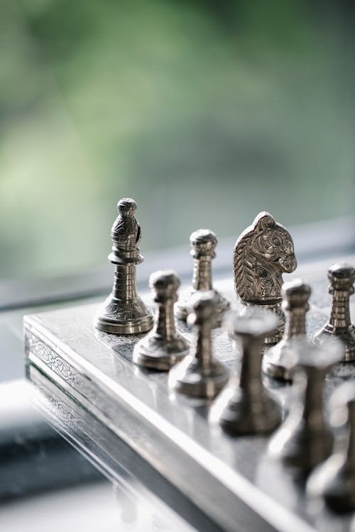 Metal chess pieces on board in room