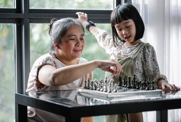 Asian Woman Playing Chess With Granddaughter