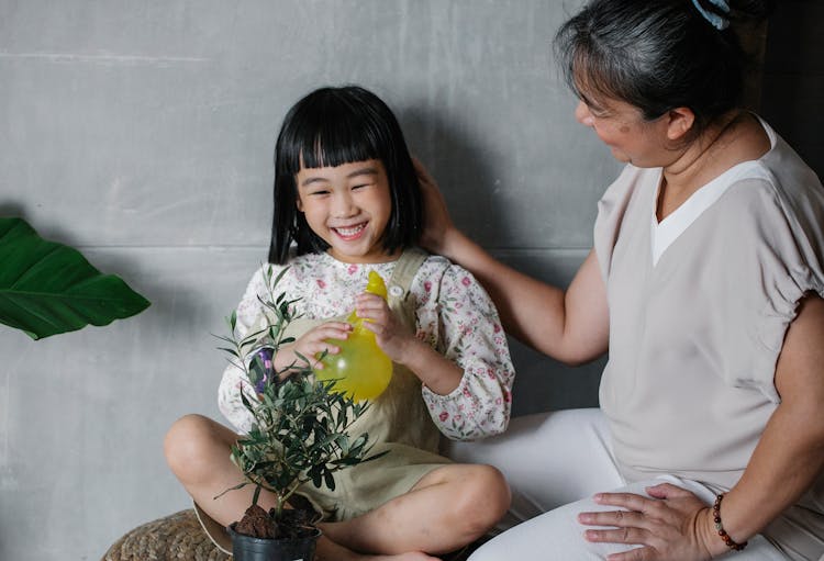 Laughing Girl With Grandmother Taking Care Of Plant