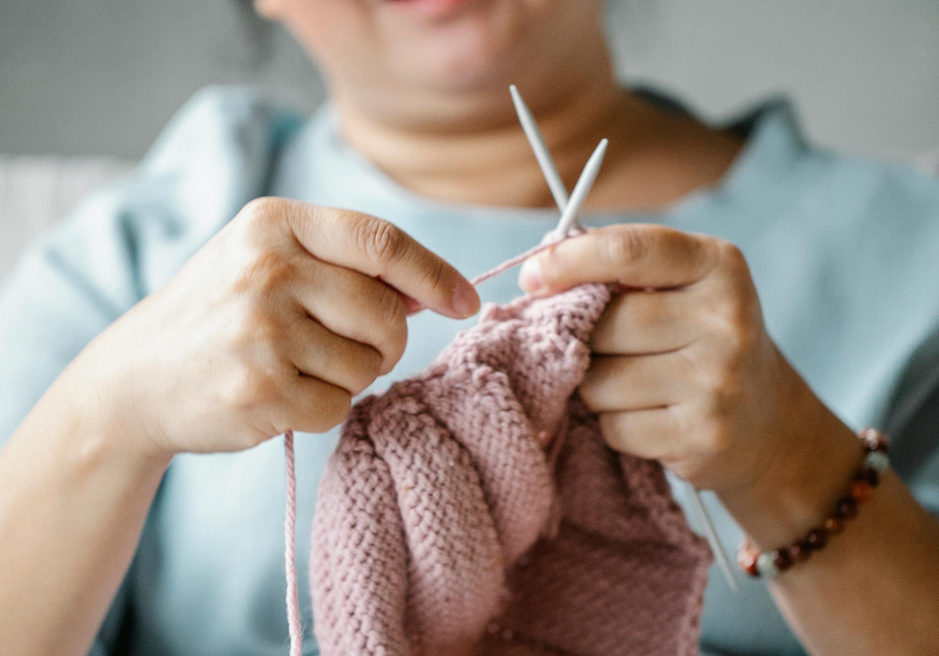 faceless female knitting of pink yarn