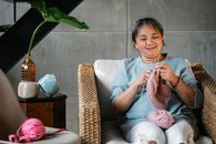 一位中年亚洲妇女在家中舒适地编织，享受轻松时刻