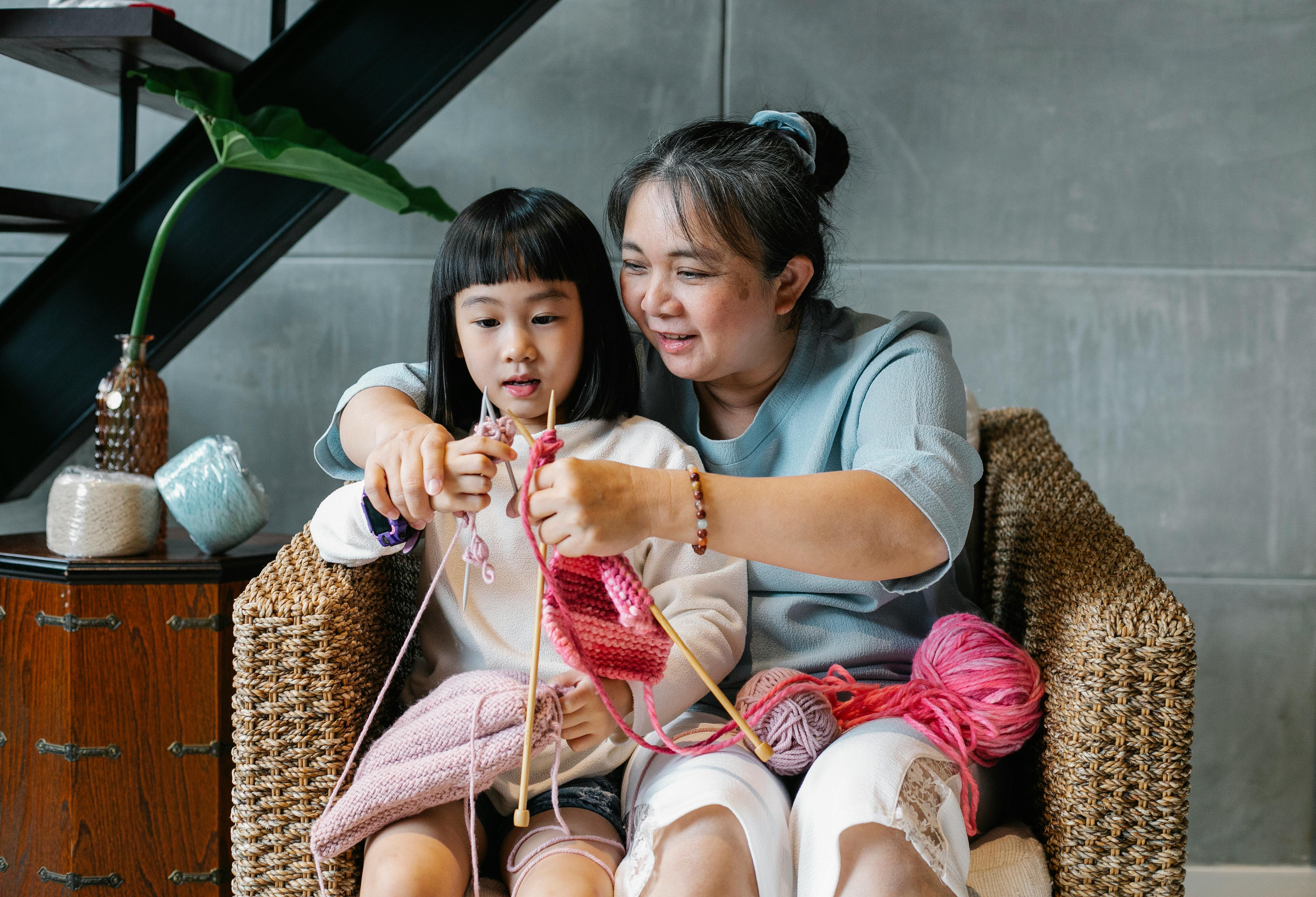 smiling woman showing girl knitting technique