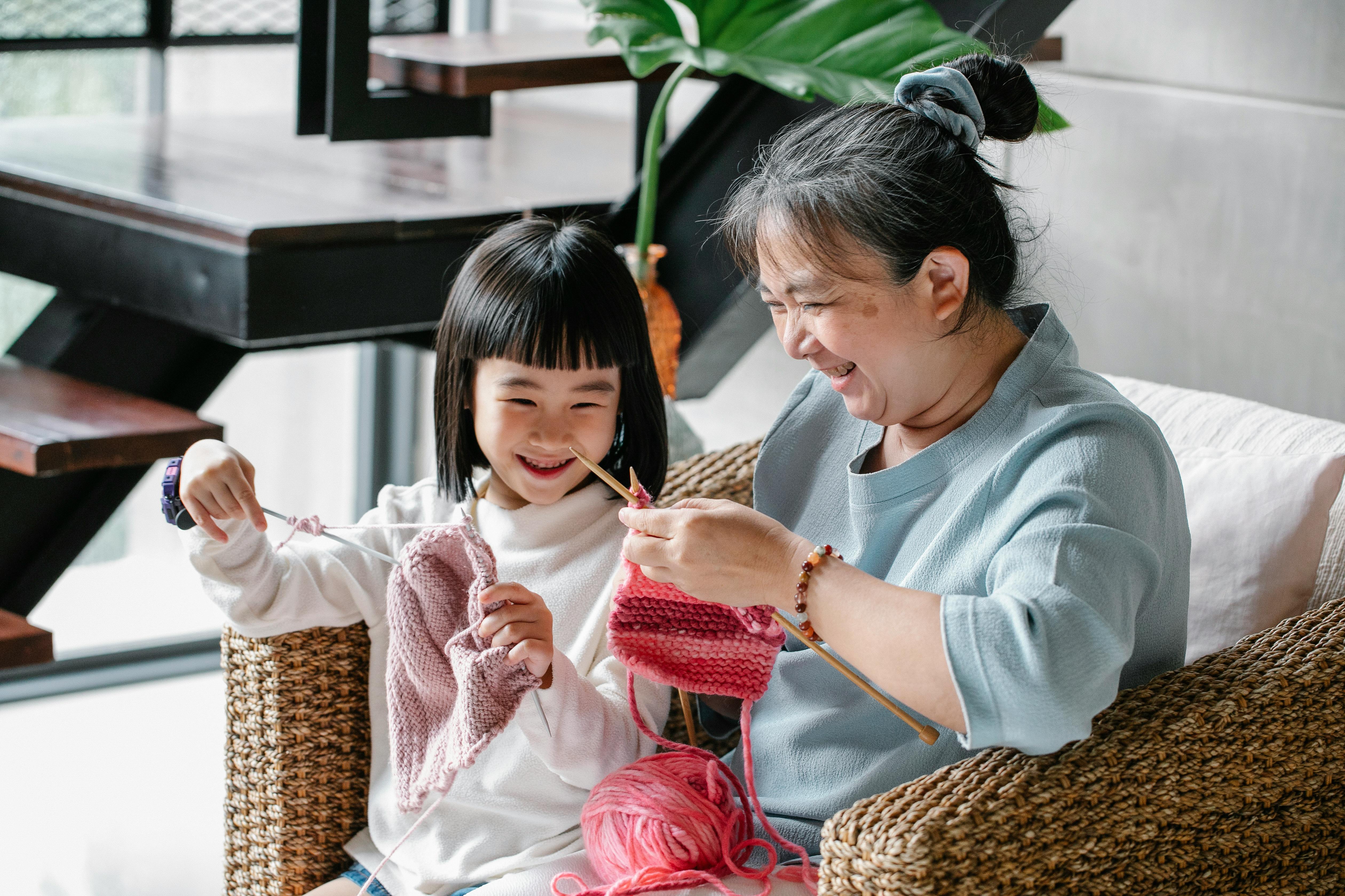 happy woman and girl knitting at home