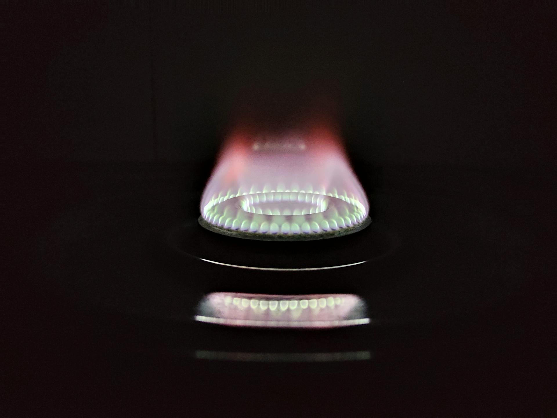 A vivid and detailed view of a gas stove flame glowing against a dark background.