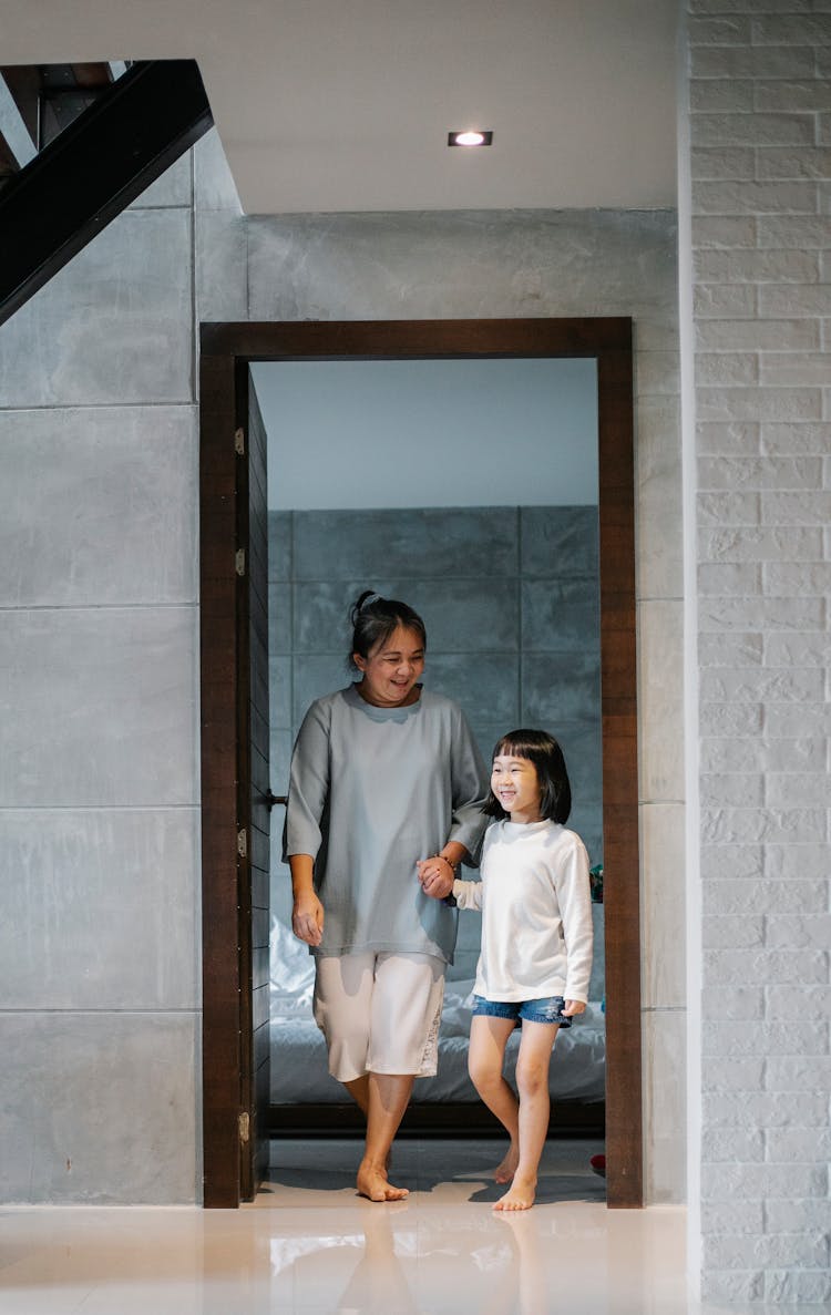 Happy Ethnic Grandmother With Adorable Child Walking In Corridor Of Modern Mansion