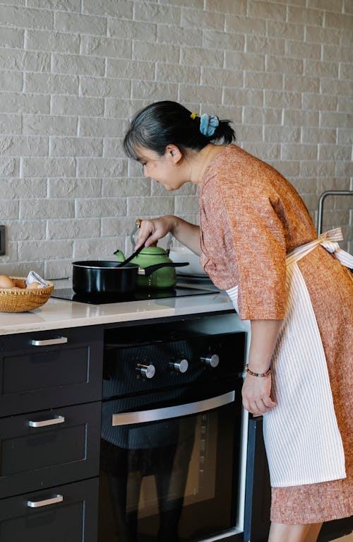 Senior Asian woman cooking dinner in modern kitchen