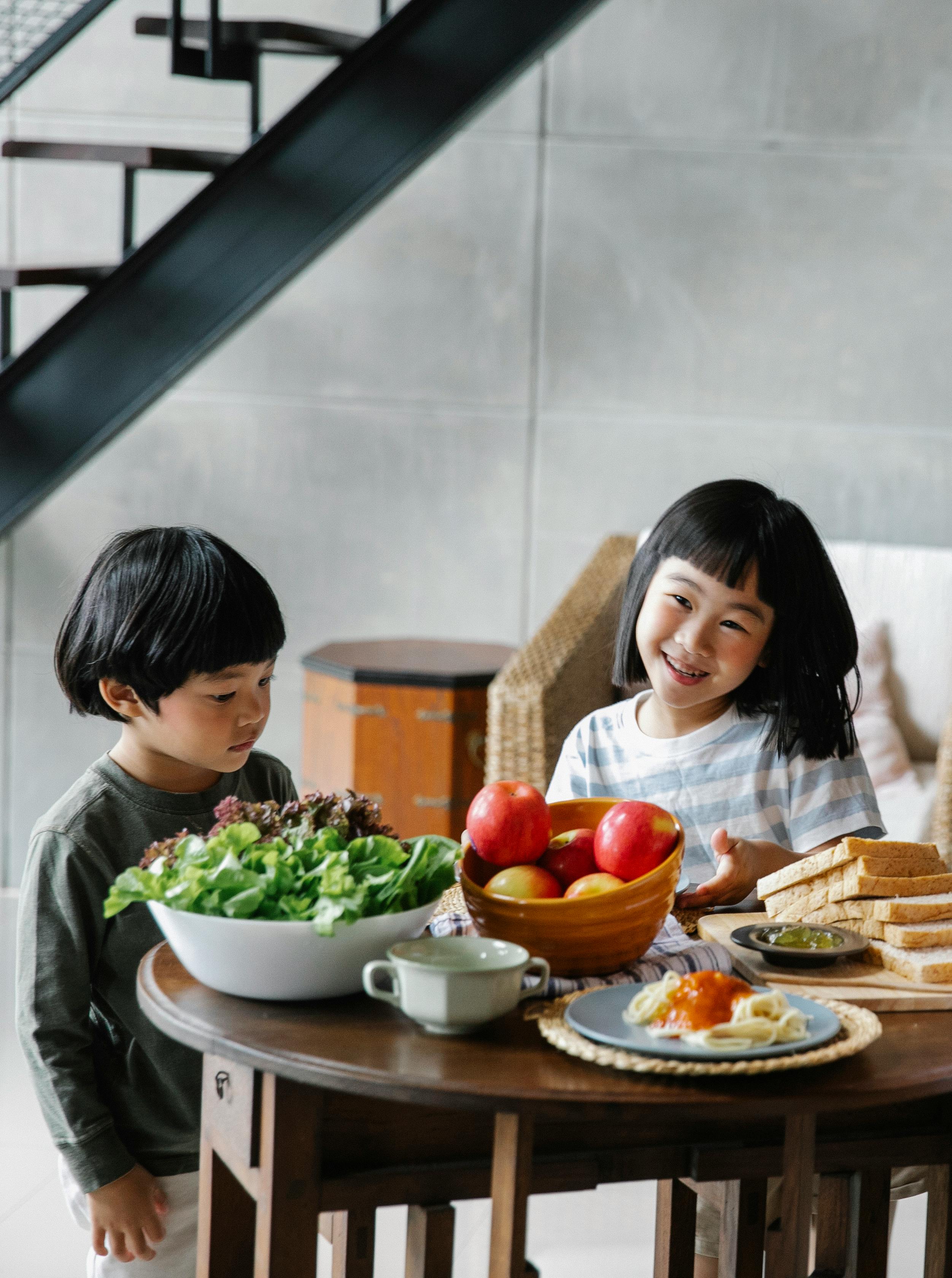 adorable ethnic little siblings having breakfast in kitchen