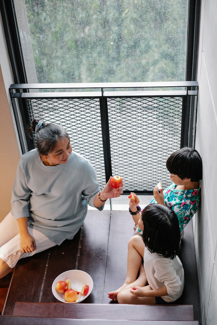 Asian Grandmother With Grandchildren Eating Healthy Delicious Fruits At Home