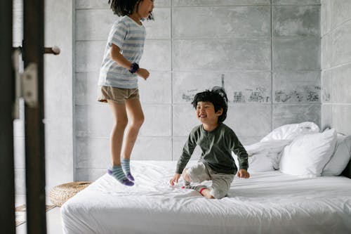 Happy ethnic kids having fun on bed